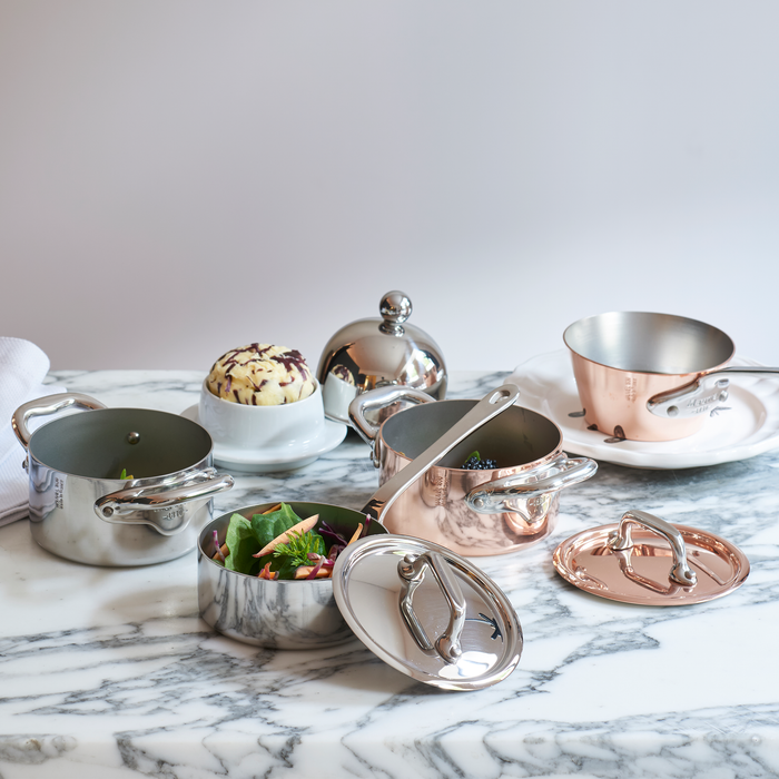 Mauviel M'MINIS stainless steel oval stewpan with brass handles and lid, 0.36-quart capacity, ideal for small stovetop cooking.