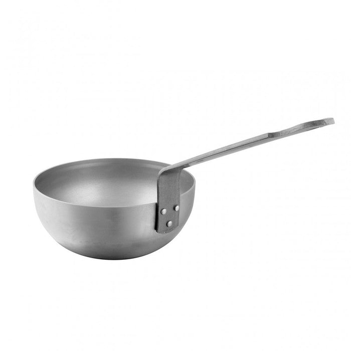Mauviel M'STEEL black carbon steel chef pan with iron handle, shown from a side angle on a kitchen surface.